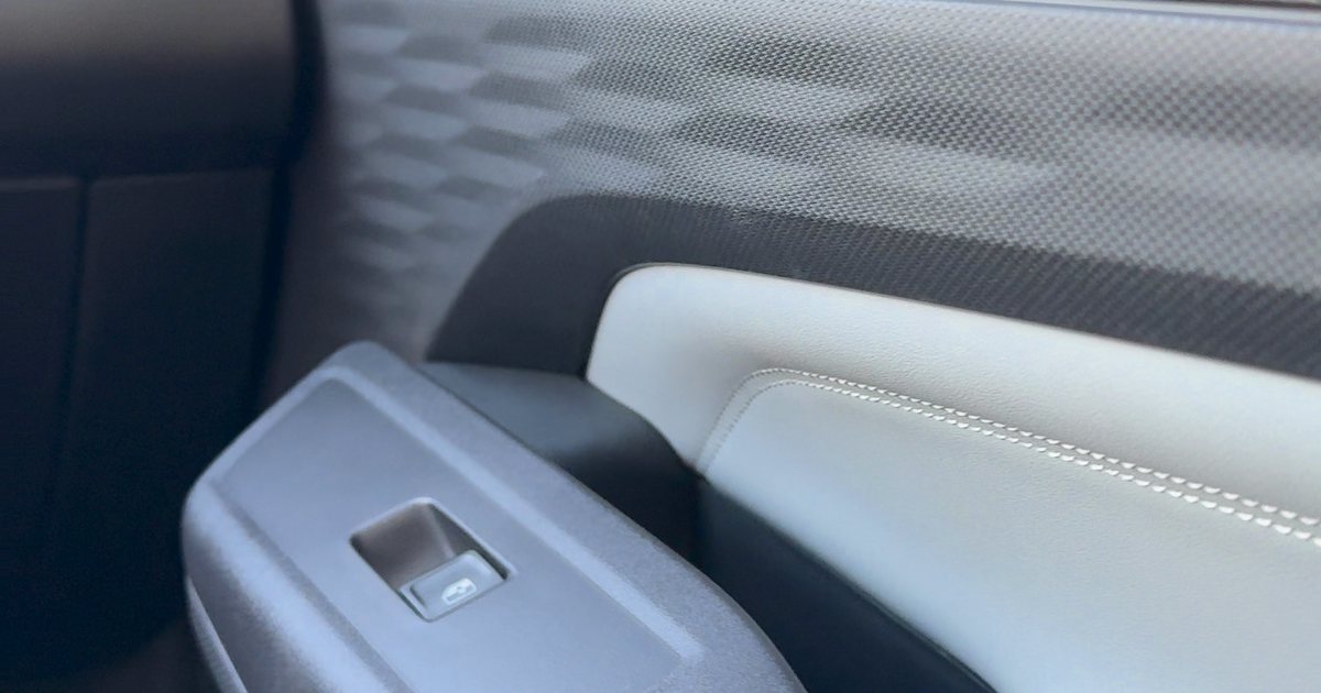 Detalhe do interior de um carro 0km, com acabamento claro e comandos na porta